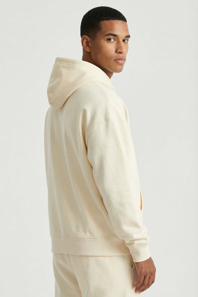 Man wearing a beige hoodie and pants on a white background
