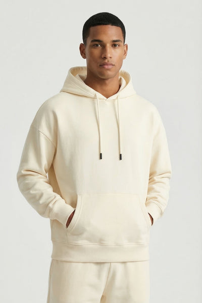 Man wearing a cream hoodie and pants on a white background