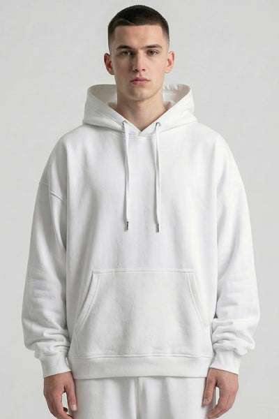 Person wearing a white hoodie and pants on a plain background