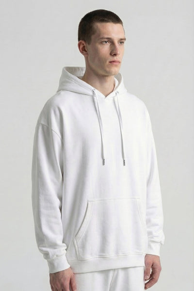 Person wearing a plain white hoodie and pants on a light gray background
