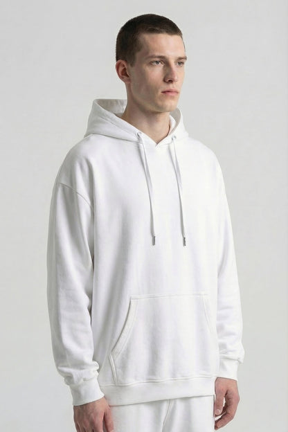 Person wearing a plain white hoodie and pants on a light gray background