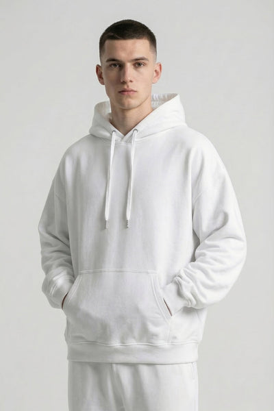 Person wearing a white hoodie and pants on a plain background