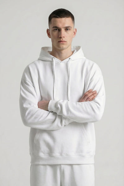 Person wearing a white hoodie and pants against a plain background