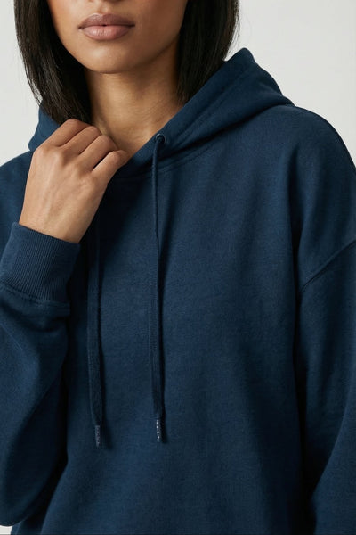 Woman wearing a navy blue hoodie against a plain background