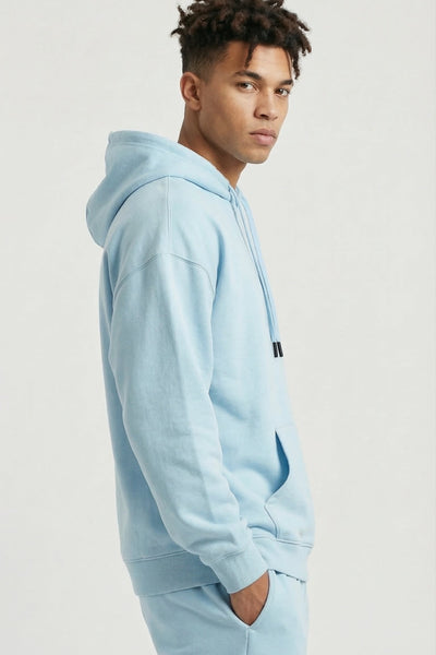 Person wearing a light blue hoodie and pants on a plain background