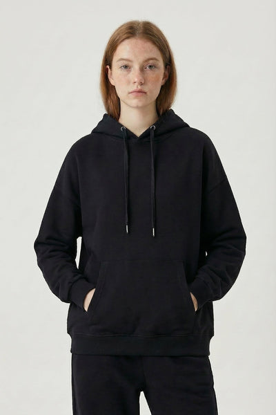 Person wearing a black hoodie and pants on a white background