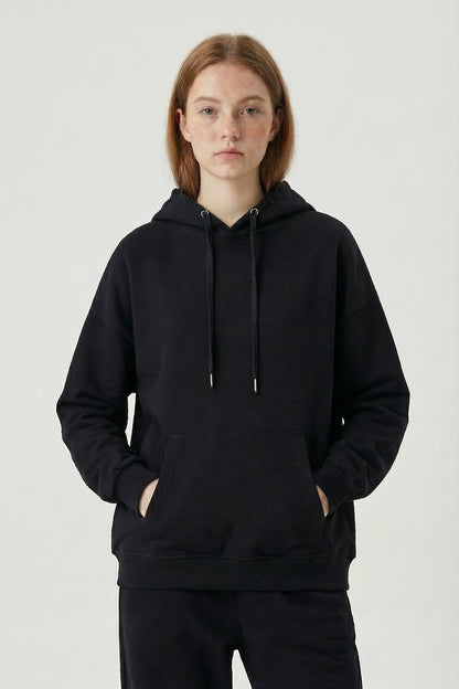 Person wearing a black hoodie and pants on a white background