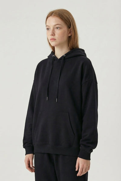 Person wearing a black hoodie and pants on a light gray background