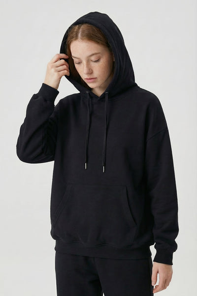 Person wearing a black hoodie and pants on a white background