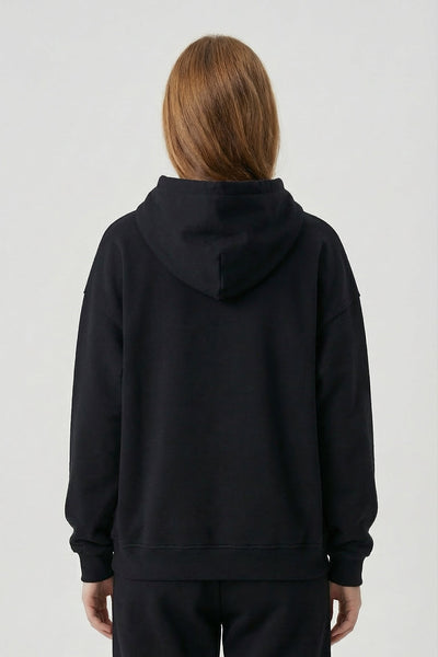 Person wearing a black hoodie and pants on a white background
