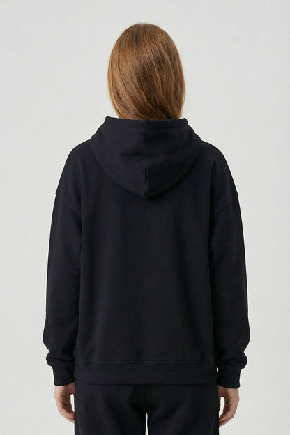 Person wearing a black hoodie and pants on a white background