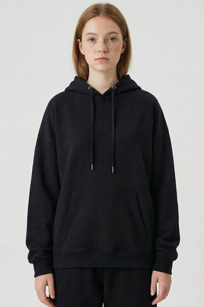 Person wearing a black hoodie and pants on a white background