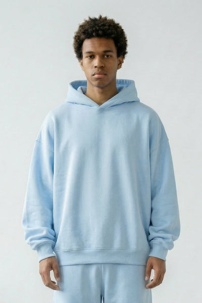 Person wearing a light blue hoodie and pants set on a plain background