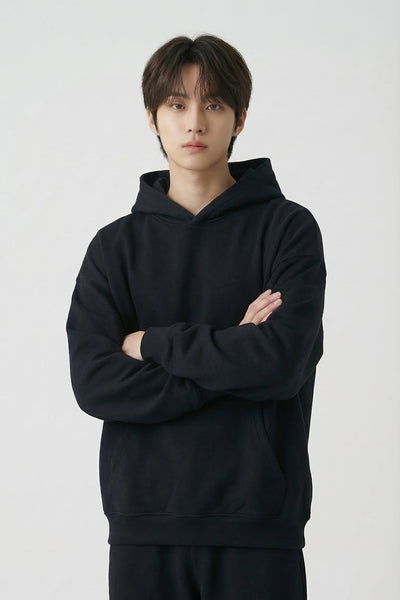 Person wearing a black hoodie and pants on a white background