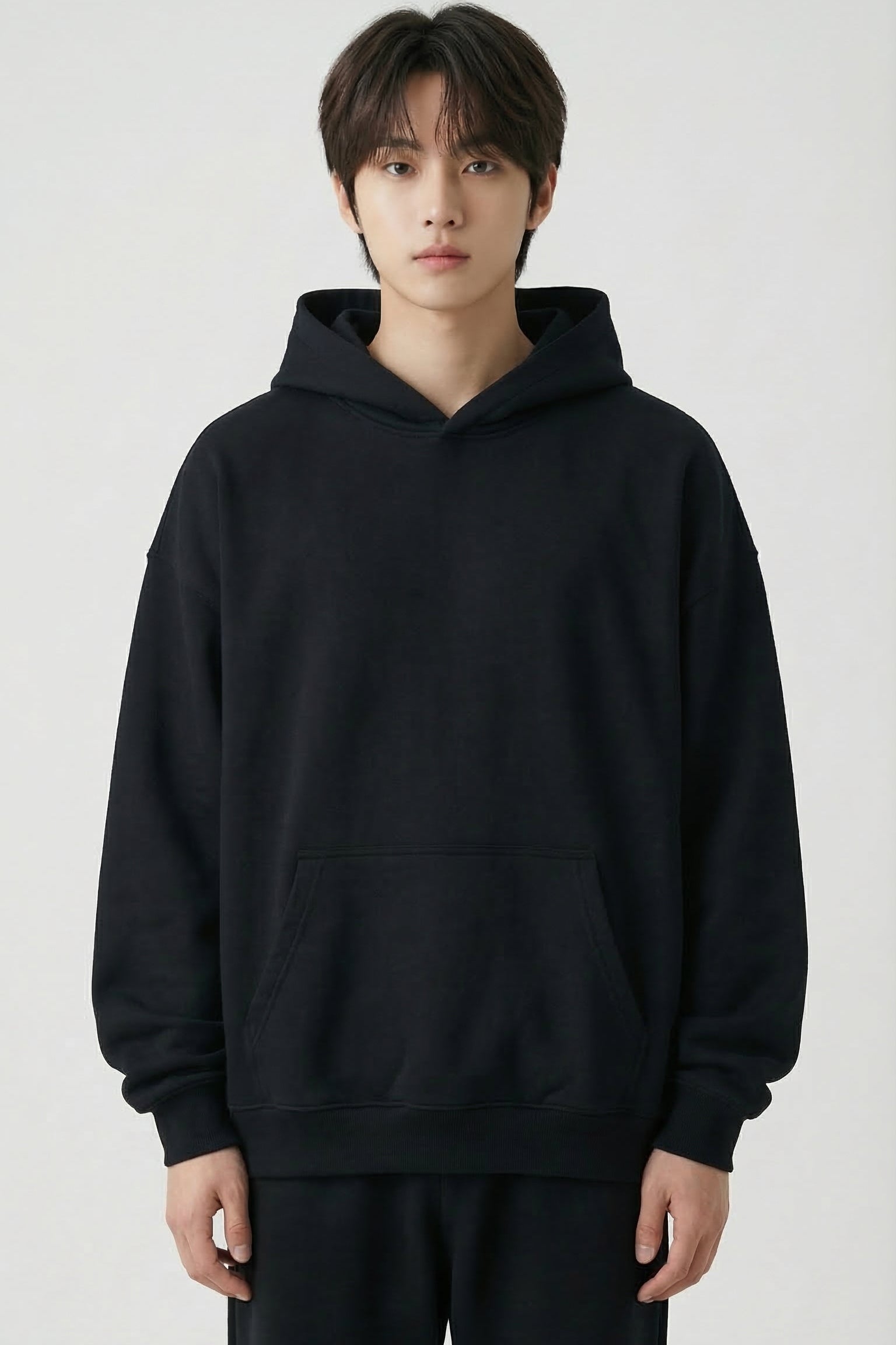 Person wearing a black hoodie and pants on a white background