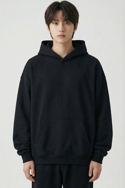Person wearing a black hoodie and pants on a white background