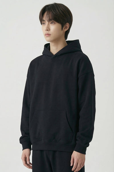 Person wearing a black hoodie and pants on a white background