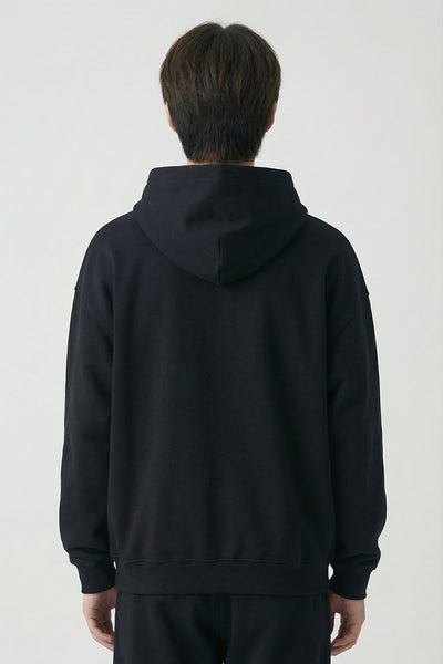 Person wearing a black hoodie and pants on a white background