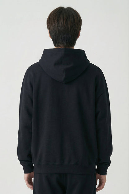 Person wearing a black hoodie and pants on a white background