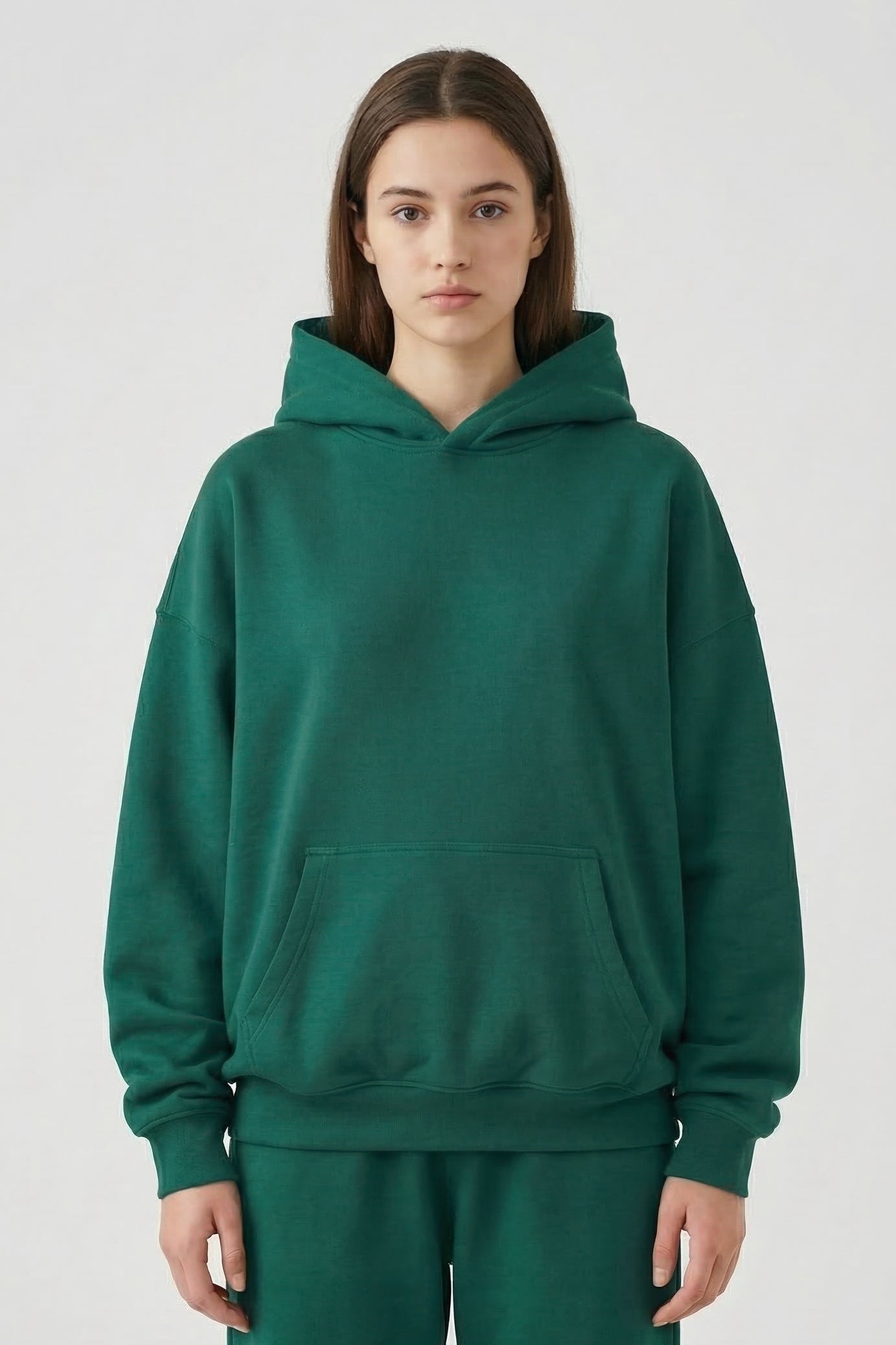 Person wearing a green hoodie and pants on a white background
