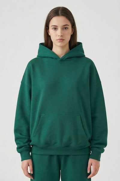 Person wearing a green hoodie and pants on a white background