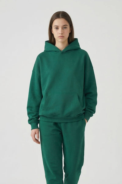 Person wearing a green hoodie and matching pants on a white background