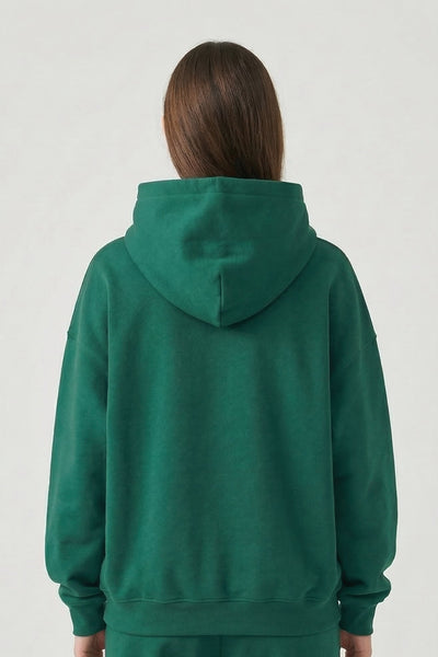 Person wearing a green hoodie and pants on a white background