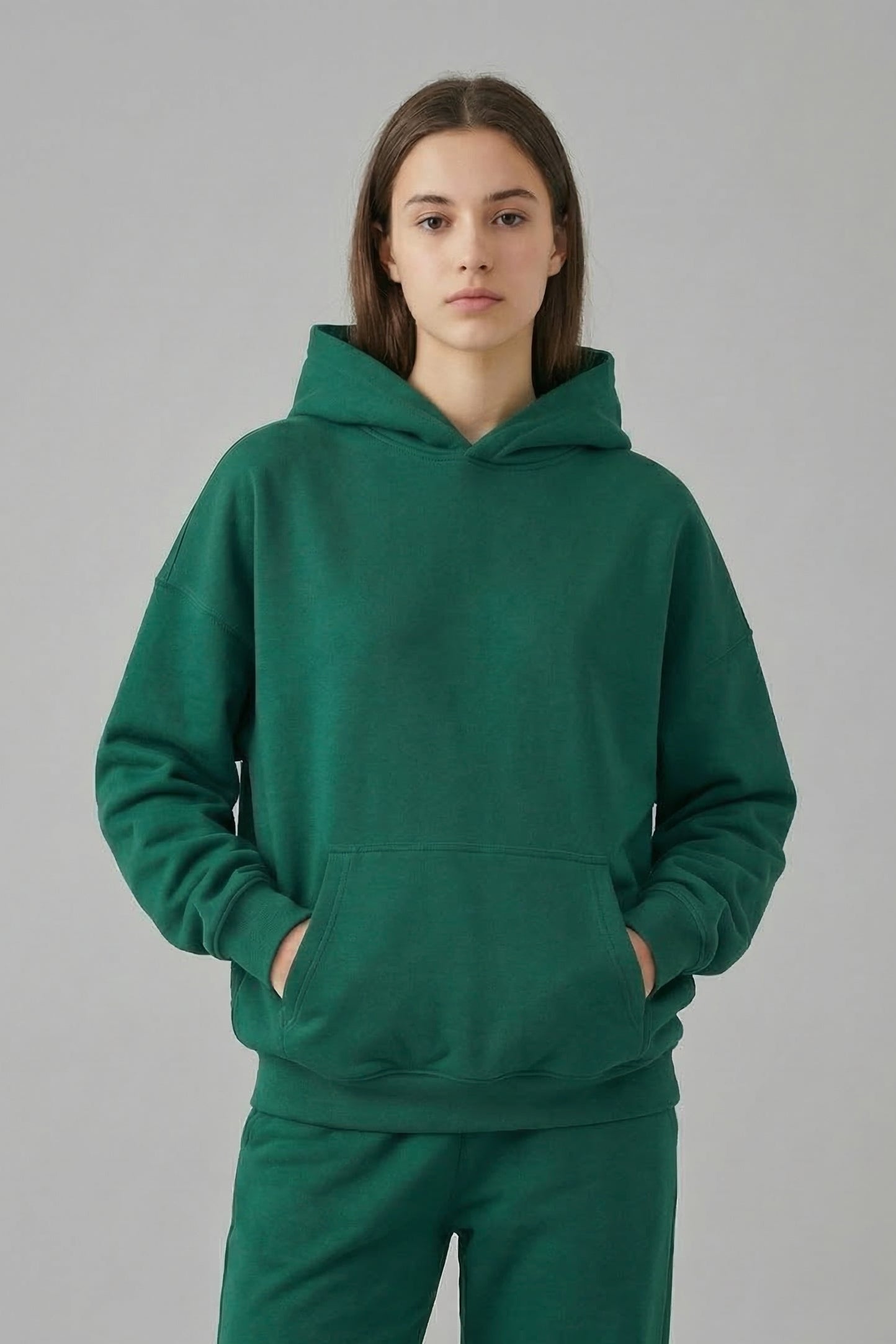 Person wearing a green hoodie and pants on a gray background