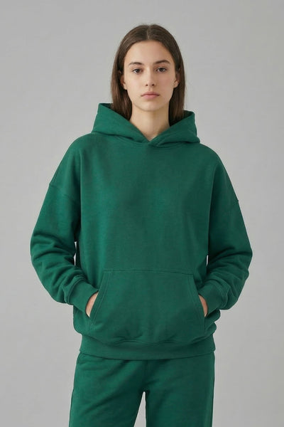 Person wearing a green hoodie and pants on a gray background