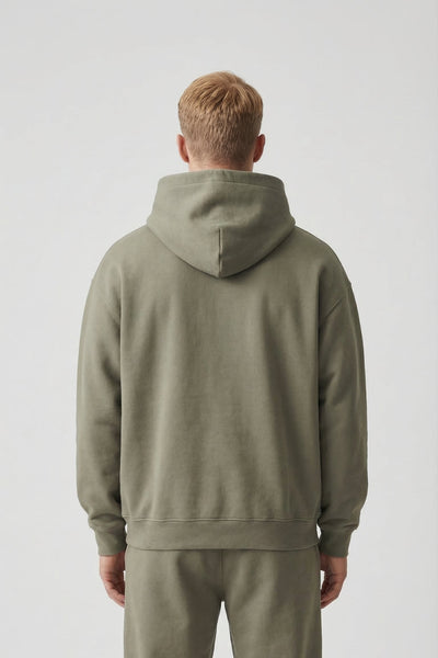 Person wearing a green hoodie and pants on a white background