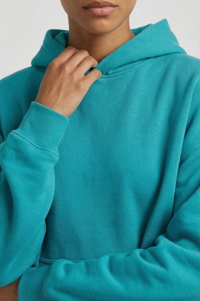 Person wearing a teal hoodie against a white background