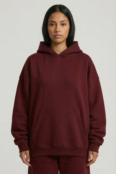Person wearing a burgundy hoodie and pants on a plain background