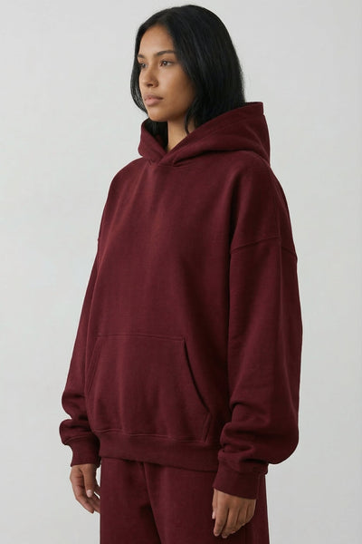 Person wearing a maroon hoodie and pants on a white background