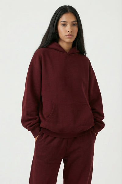 Person wearing a burgundy hoodie and pants on a white background