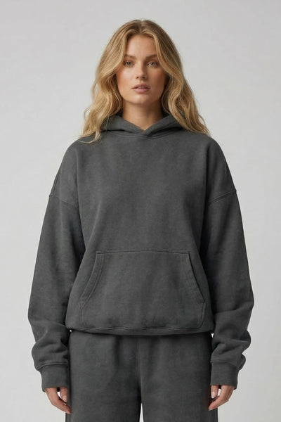 Person wearing a gray hoodie and pants set on a plain background