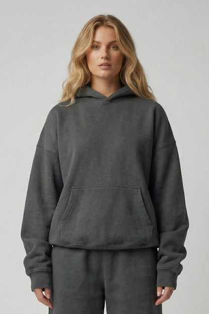 Person wearing a gray hoodie and pants set on a plain background