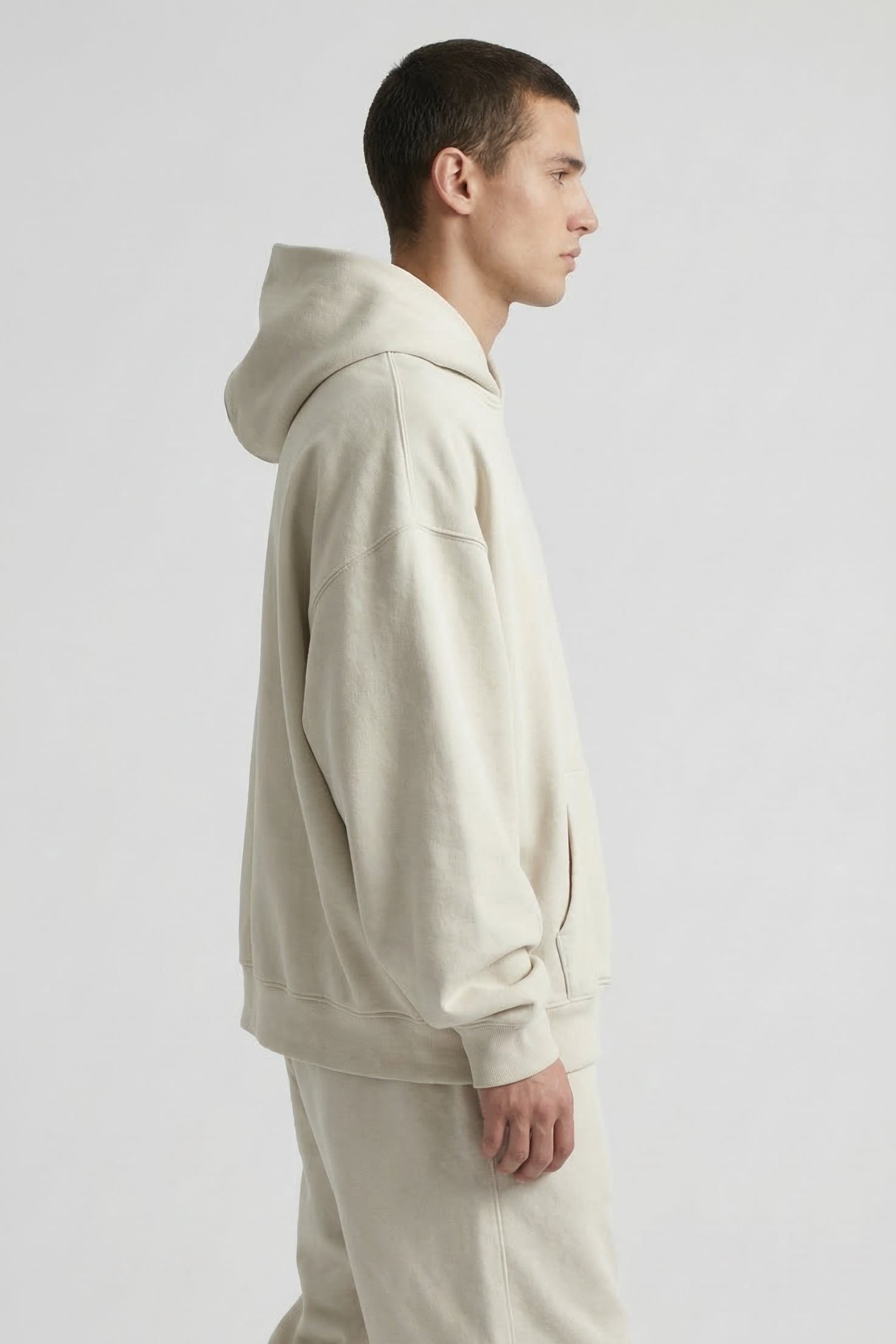 Man wearing a beige hoodie and pants on a white background