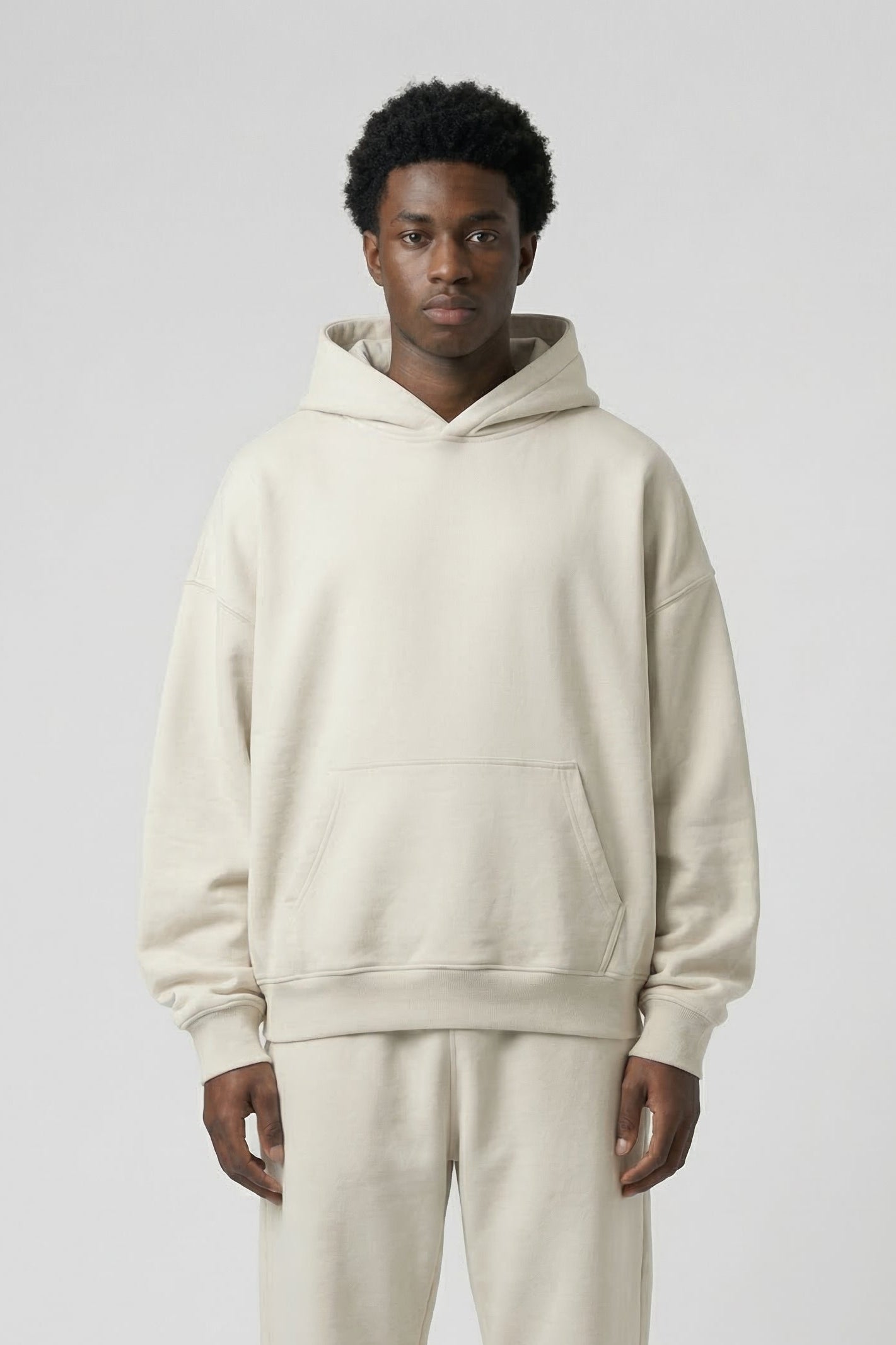 Person wearing a beige hoodie and pants on a white background