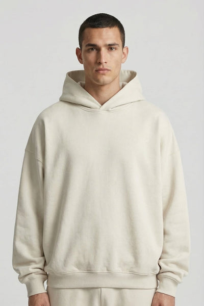 Man wearing a beige hoodie and pants on a plain background