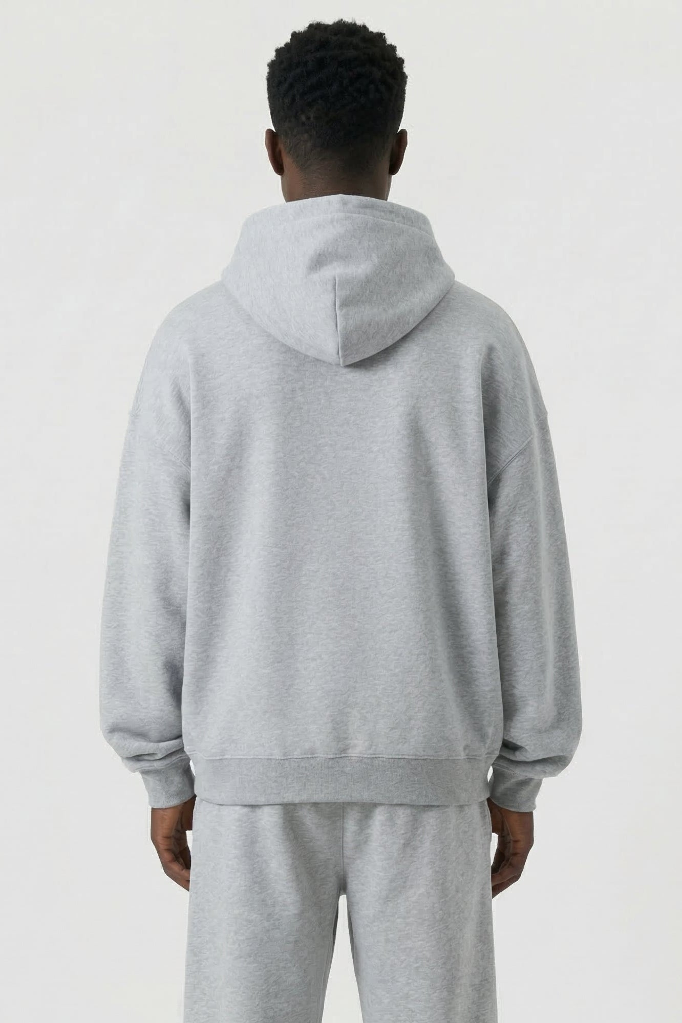 Person wearing a gray tracksuit on a white background
