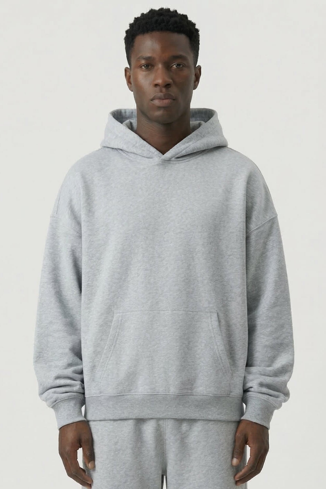 Person wearing a gray hoodie and pants on a white background