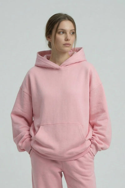 Person wearing a pink hoodie and pants on a plain background
