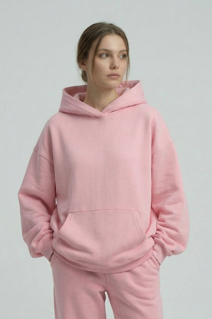 Person wearing a pink hoodie and pants on a plain background