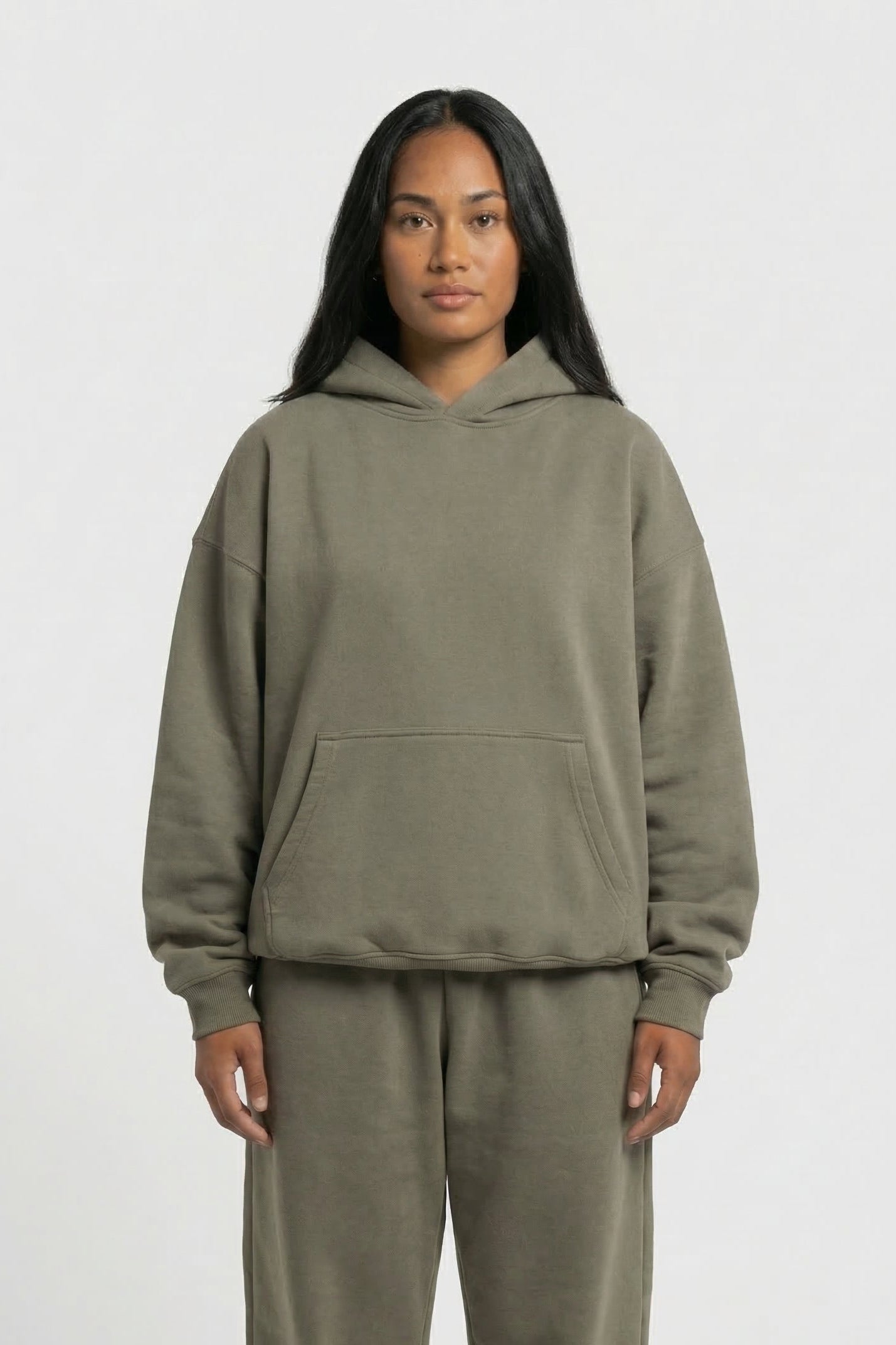 Person wearing a green hoodie and pants set on a white background