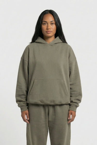 Person wearing a green hoodie and pants set on a white background