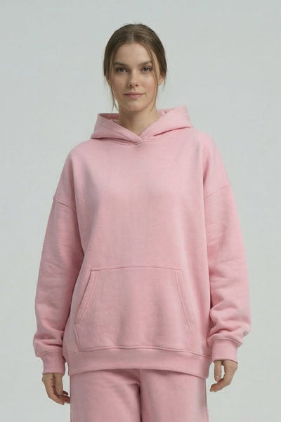 Person wearing a pink hoodie and pants set on a white background