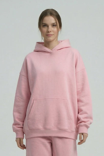 Person wearing a pink hoodie and pants set on a white background