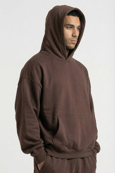 Man wearing a brown hoodie and pants on a white background