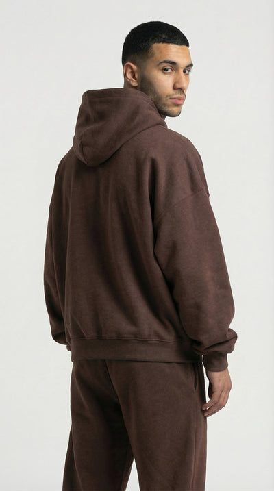 Man wearing a brown hoodie and pants on a white background