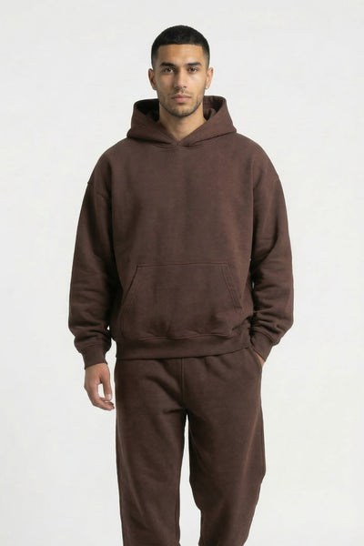 Man wearing a brown hoodie and pants set on a white background